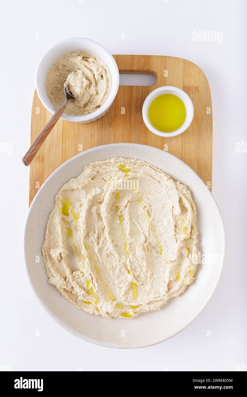 hummus on plate with olive oil on wooden cutting board on white background Stock Photo