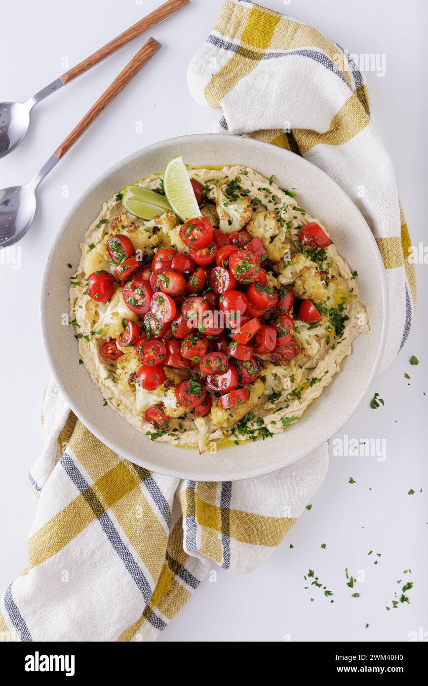 Roast cauliflower tomatoes and hummus salad on a white background topview Stock Photo