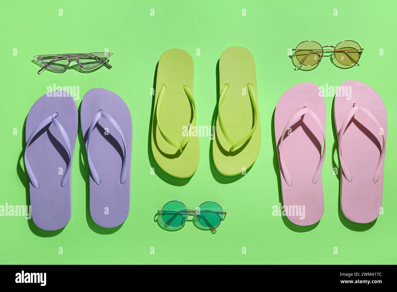Colorful pairs of flip flops and sunglasses on green background Stock ...
