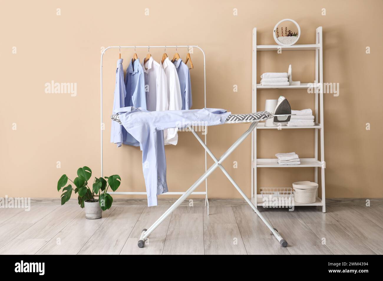 Interior of laundry room with rack, shelving unit and ironing board ...
