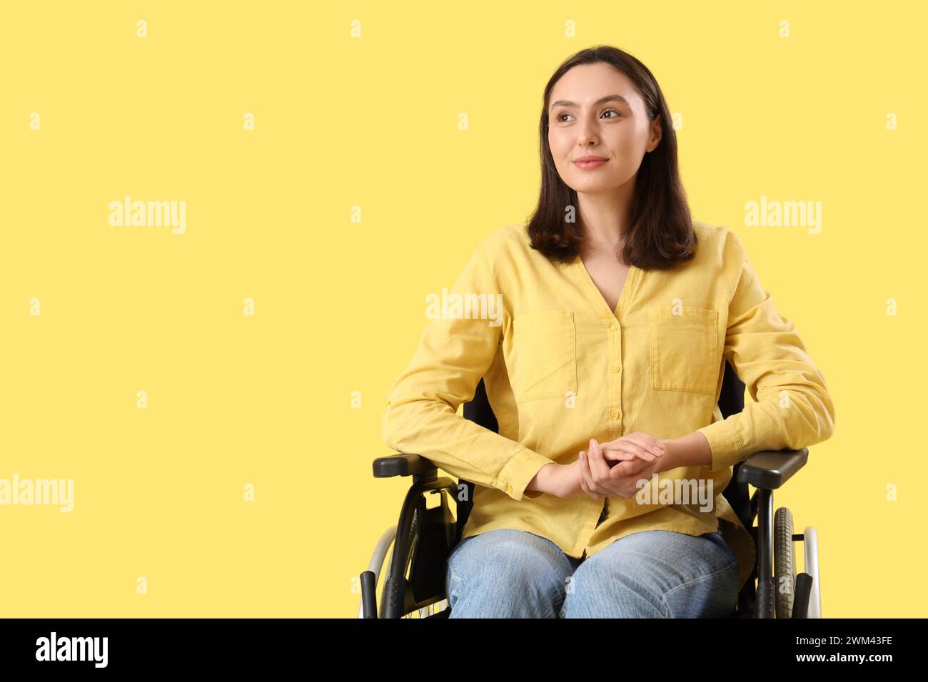 Happy young woman in wheelchair on yellow background Stock Photo - Alamy