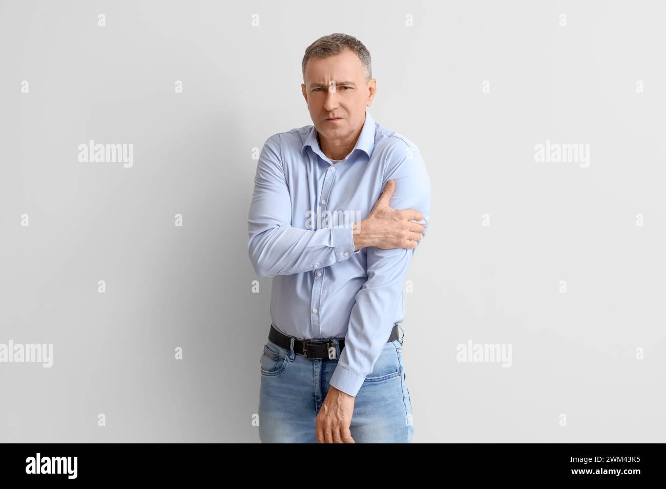 Mature man suffering from shoulder pain on light background Stock Photo ...