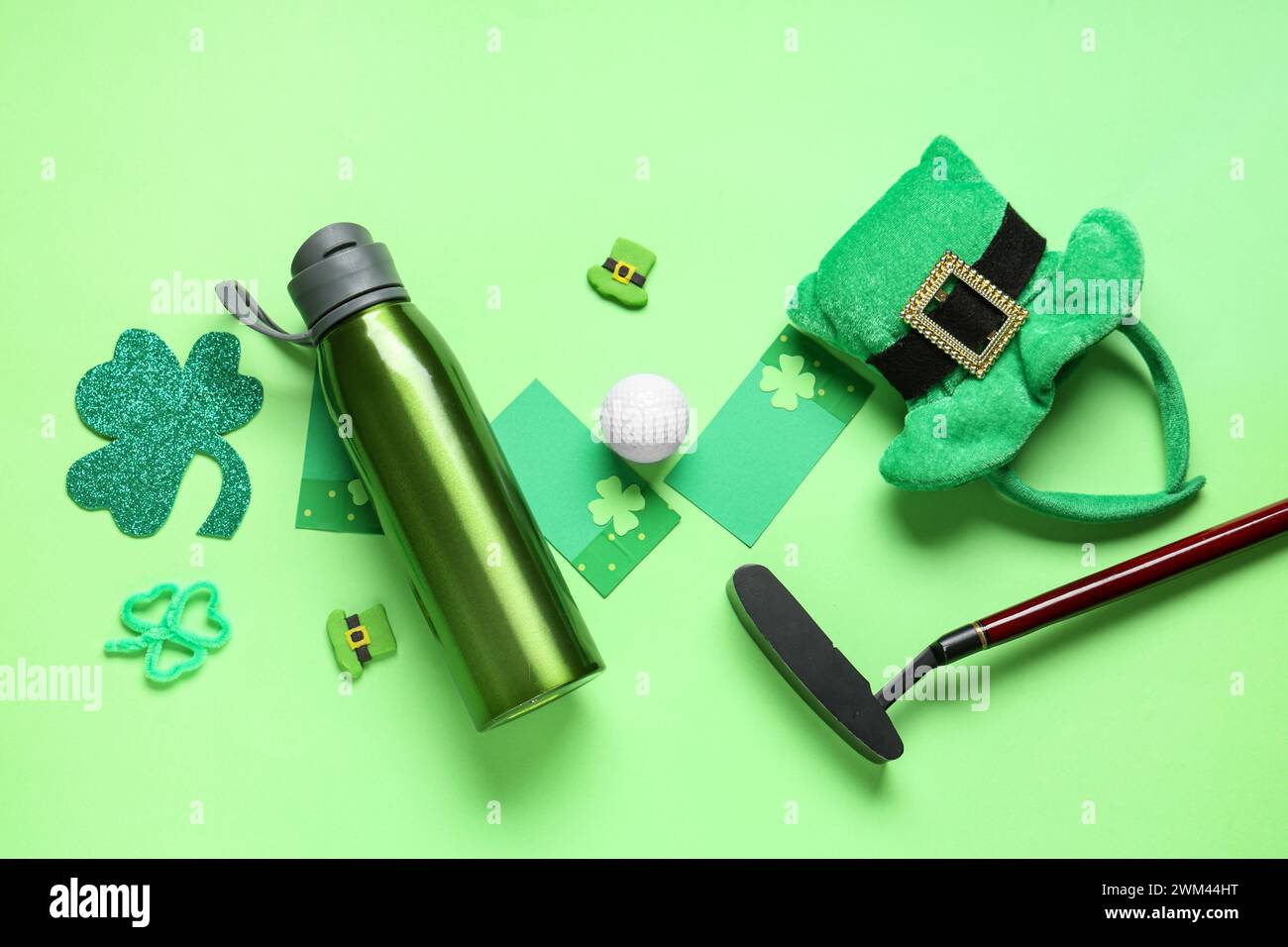 Water bottle, golf club, clovers and leprechaun's hats on green background. St. Patrick's Day