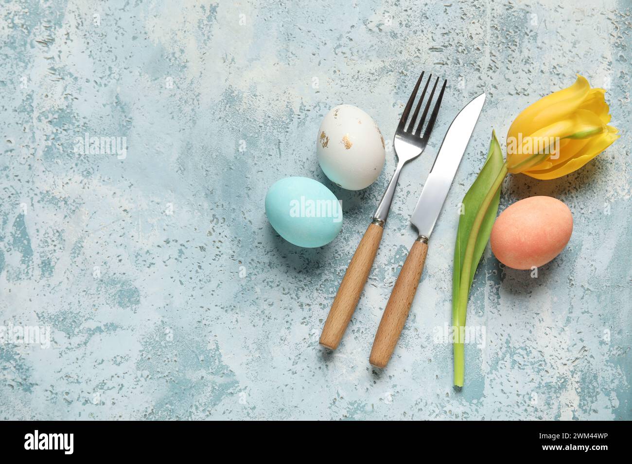 Cutlery for table setting with Easter eggs and yellow tulip on light ...