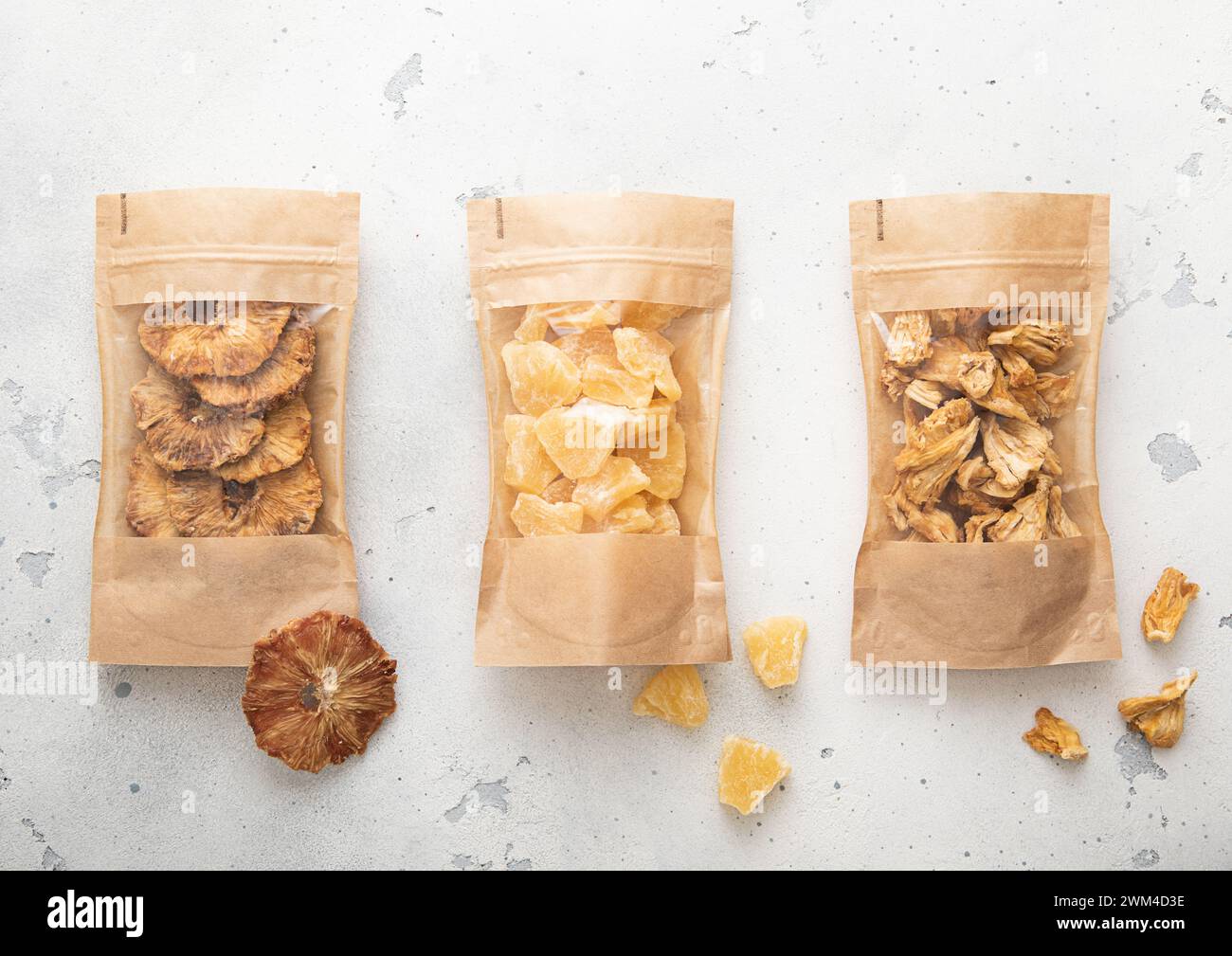 Packages with dried sweet pineapple slices and chips on light background. Stock Photo