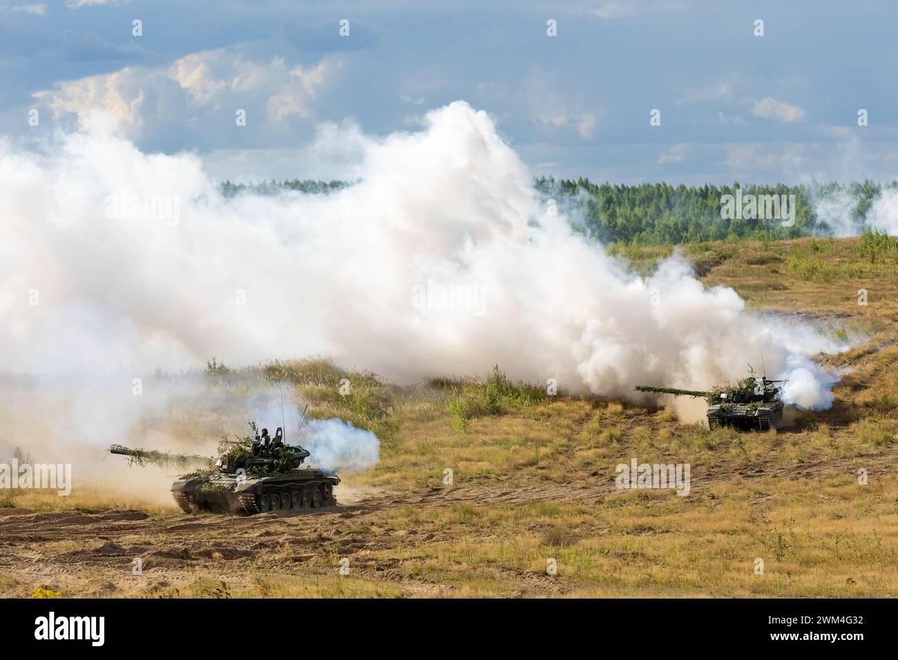 Heavy combat vehicles tanks drive around the butts and put up a smoke ...