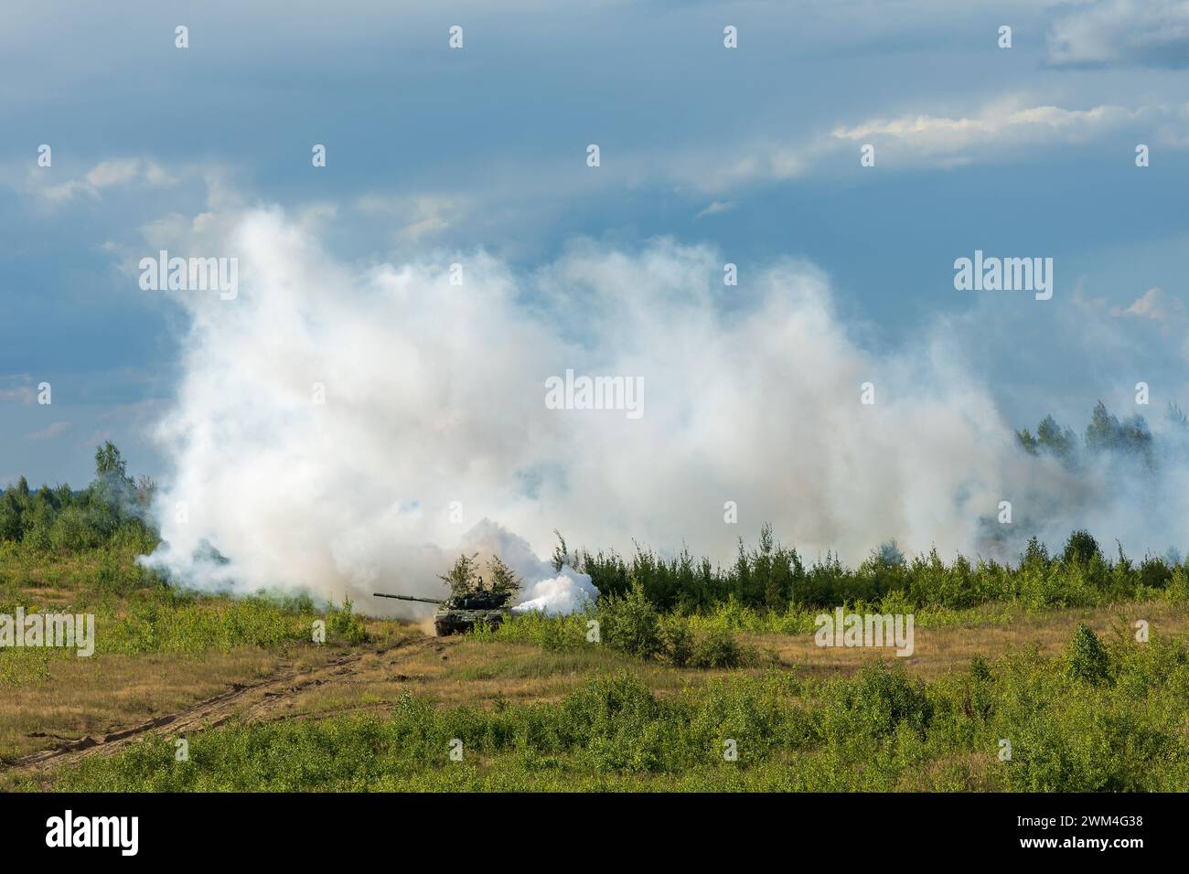 Heavy combat vehicles tanks drive around the butts and put up a smoke ...