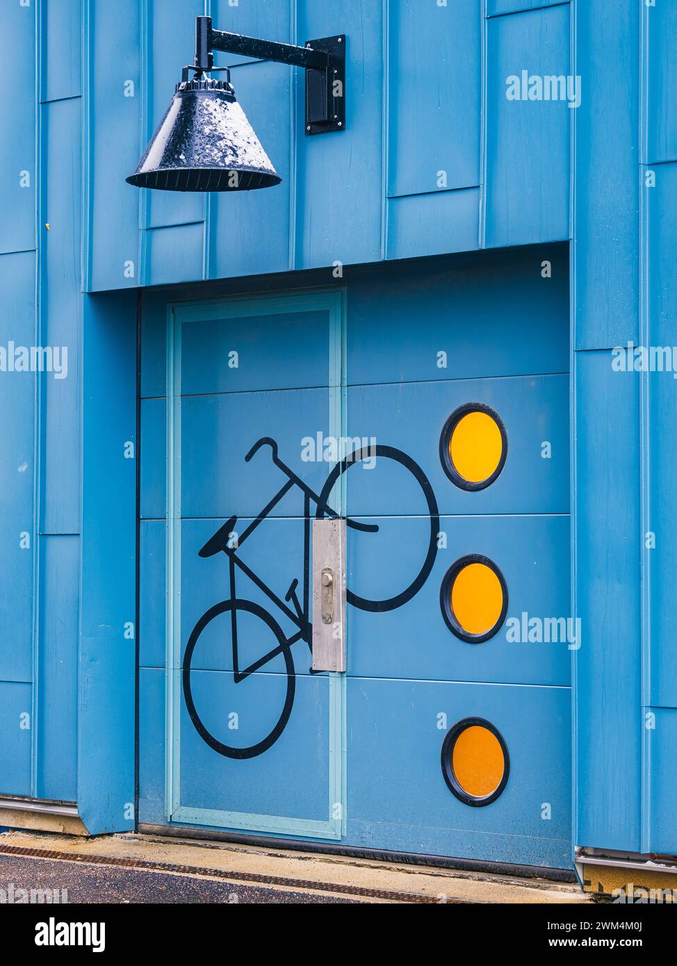 A striking blue door features a painted bicycle icon, complemented by three bright yellow circles, representing a bike-friendly facility in Gothenburg Stock Photo