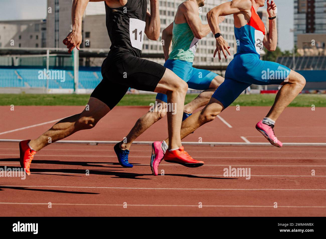 group male athletes sprinting on red track stadium, muscles taut, competing fiercely. summer sports games Stock Photo