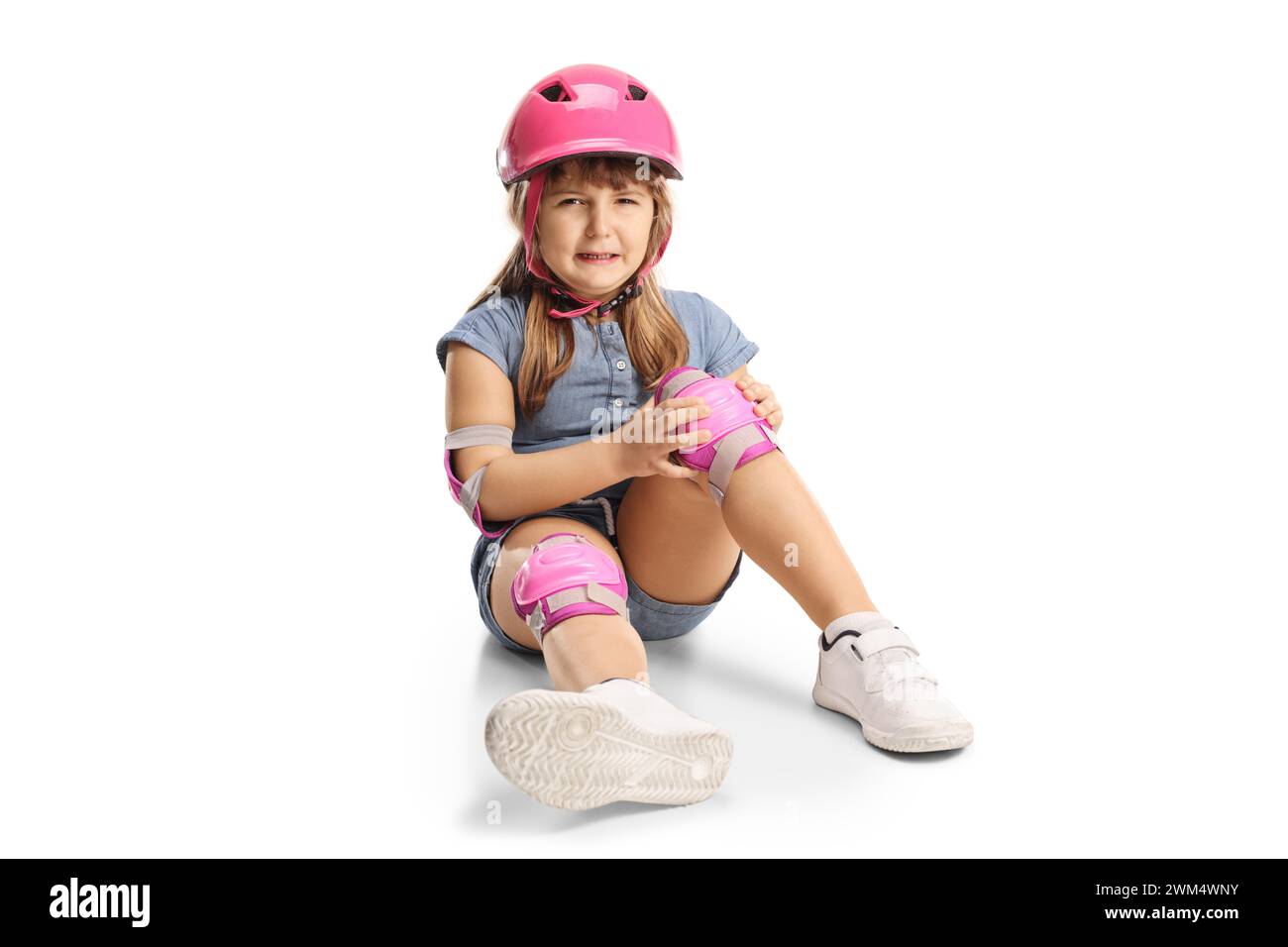 Child with a helmet and knee pads sitting on the floor and crying in
