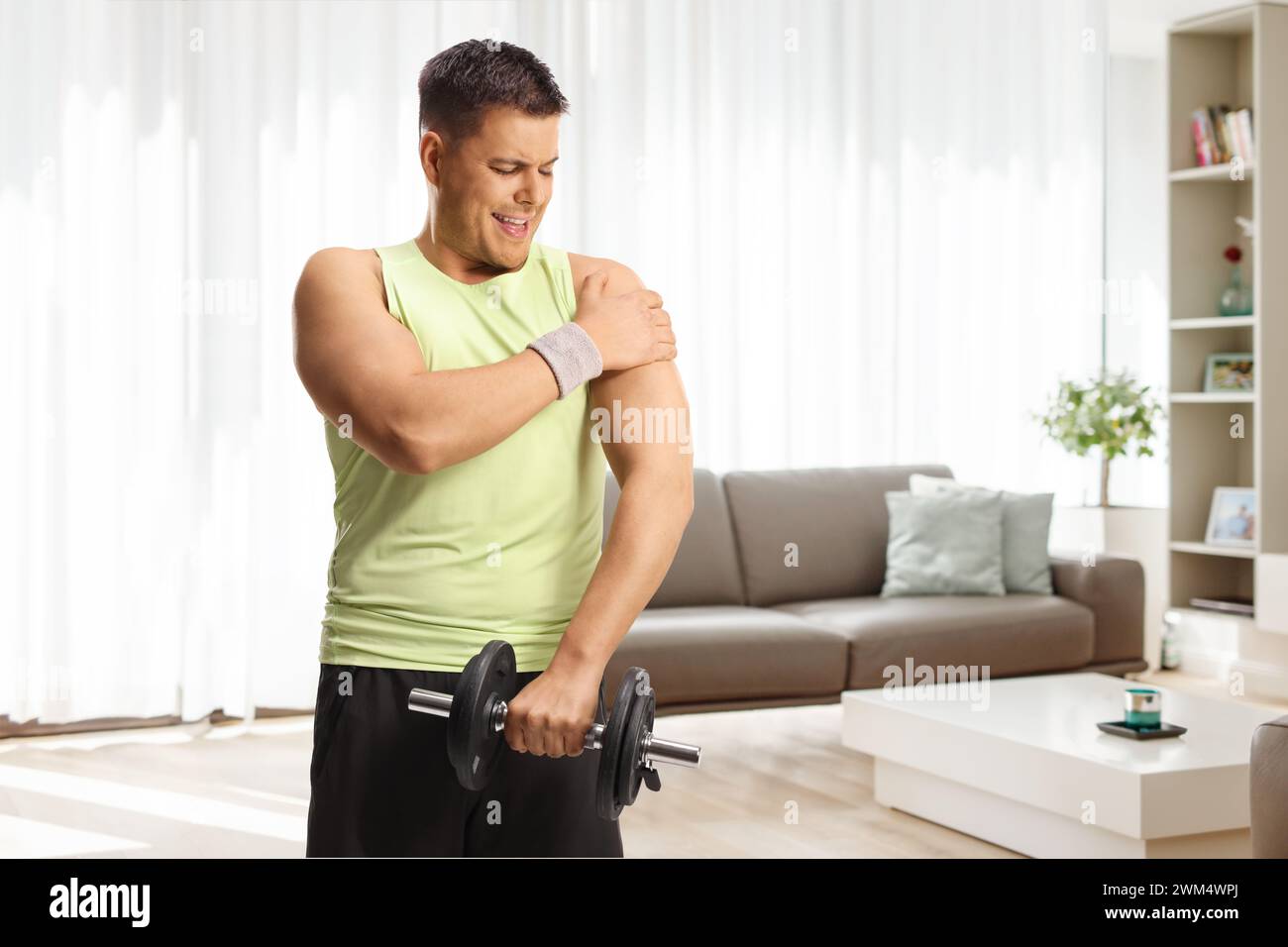 Man lifting weights at home and holding his shoulder, pain and health
