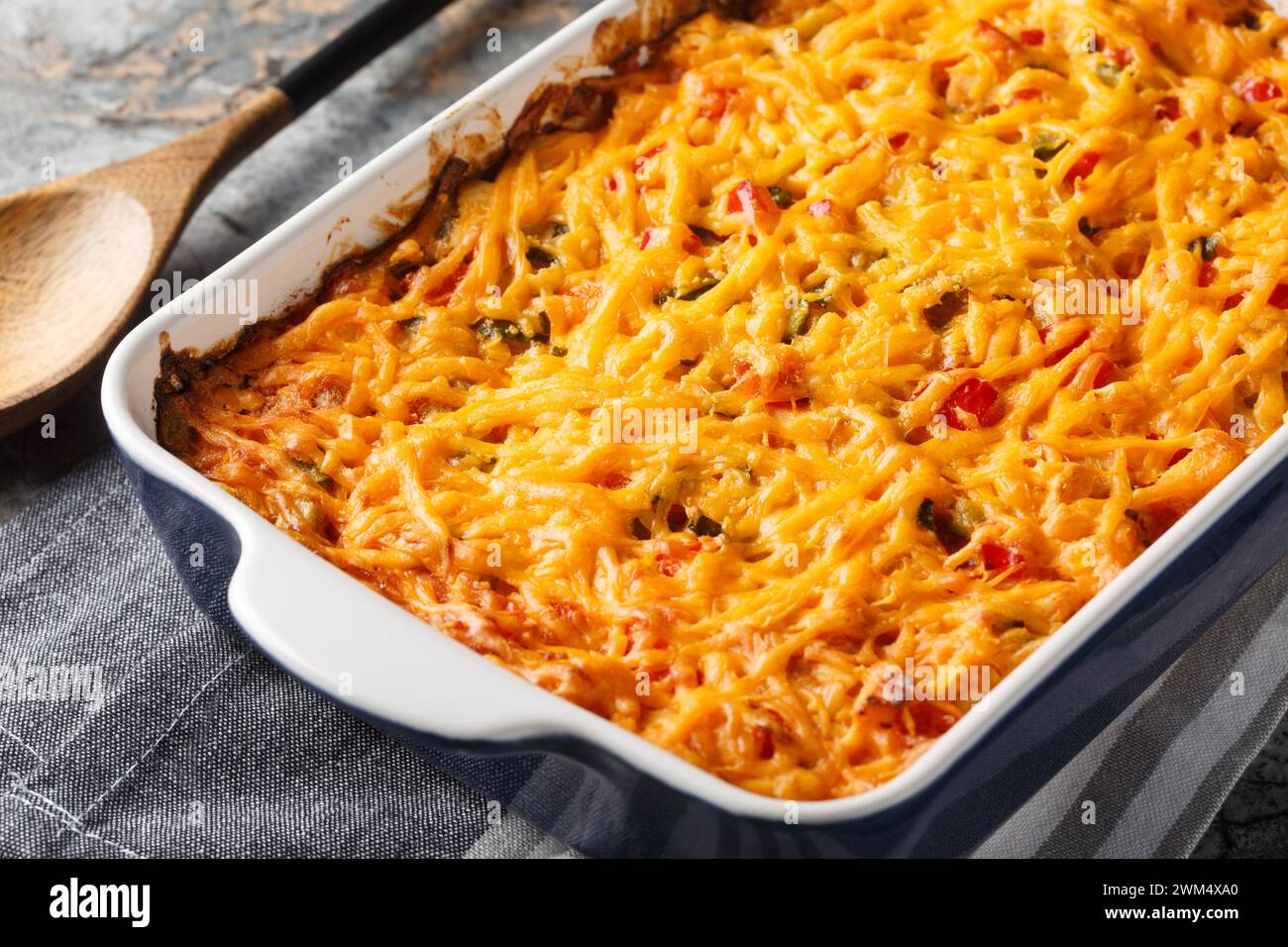 King Ranch Casserole is classic Texas comfort food with vegetables, cheddar cheese, tortilla and cream close-up in a baking dish on a marble table. Ho Stock Photo