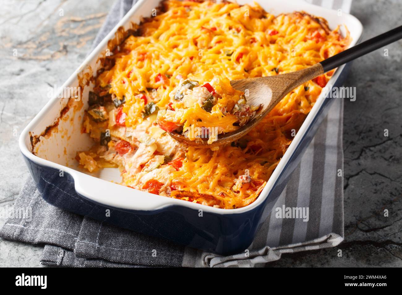 King Ranch Chicken Casserole, Tex-Mex dish of layered tortilla pieces and chicken in a spicy, cheesy sauce close-up in a baking dish on a marble table Stock Photo
