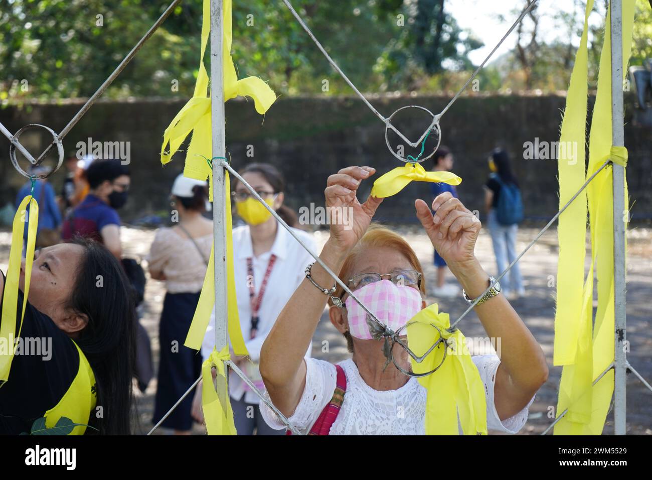 Quezon City, Philippines. 24th February 2024. Victims of human rights violation during the Martial Law and human rights advocates make ties with yellow ribbons around Bantayog ng mga Bayani during the weeklong celebration of the 38th EDSA People Power Revolution Anniversary on February 24, 2024 in Quezon City, Philippines. The initiative aims to celebrate the historic victory of the Pilipino people and reaffirm the democratic legacy of EDSA Revolution.(Credit Image: © Sherbien Dacalanio/Alamy Live News) Stock Photo