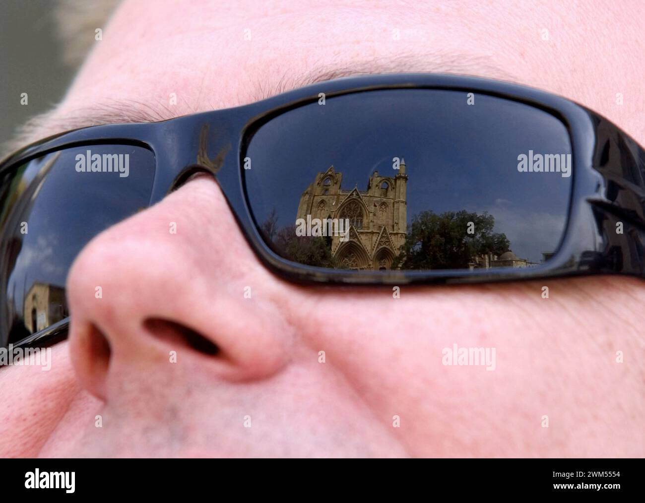Famagusta in view. The Lala Mustafa Pasha Mosque in the center of the city is reflected in a tourist's sunglasses. Stock Photo