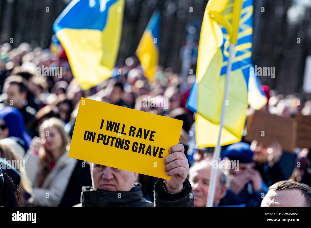 Berlin, Germany. 24th Feb, 2024. A person holds a sign reading 'I will rave on Putin's grave' at the solidarity demonstration organized by the association Vitsche 'Zusammen Demokratie verteidigen'. To mark the second anniversary of Russia's war of aggression against Ukraine, actions and rallies in solidarity with Ukraine are taking place in many places in Germany. Credit: Fabian Sommer/dpa/Alamy Live News Stock Photo