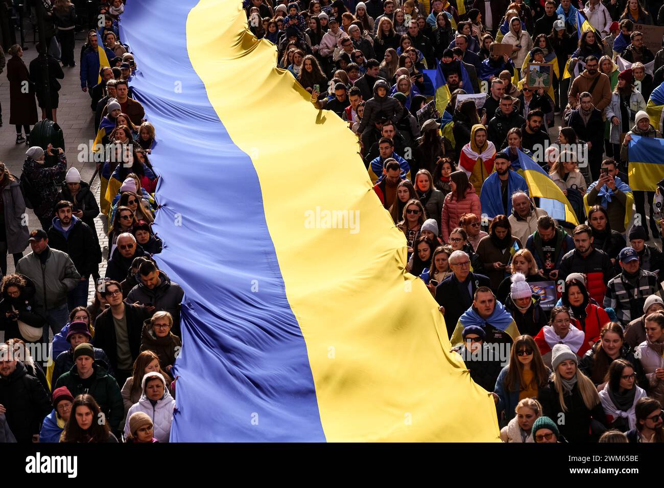 Krakow, Poland, February 24, 2024. Ukrainians and their supporters hold giant Ukrainian flag as they attend a march of support and union on the second anniversary of the full scale invasion of the Russian army on Ukraine on Florianska Street in the Old Town of Krakow. The march aims to show the unity of Ukrainian Polish people as well as display support of Russian and Belarus opposition towards Ukrainian struggle. Credit: Dominika Zarzycka/Alamy Live News Stock Photo