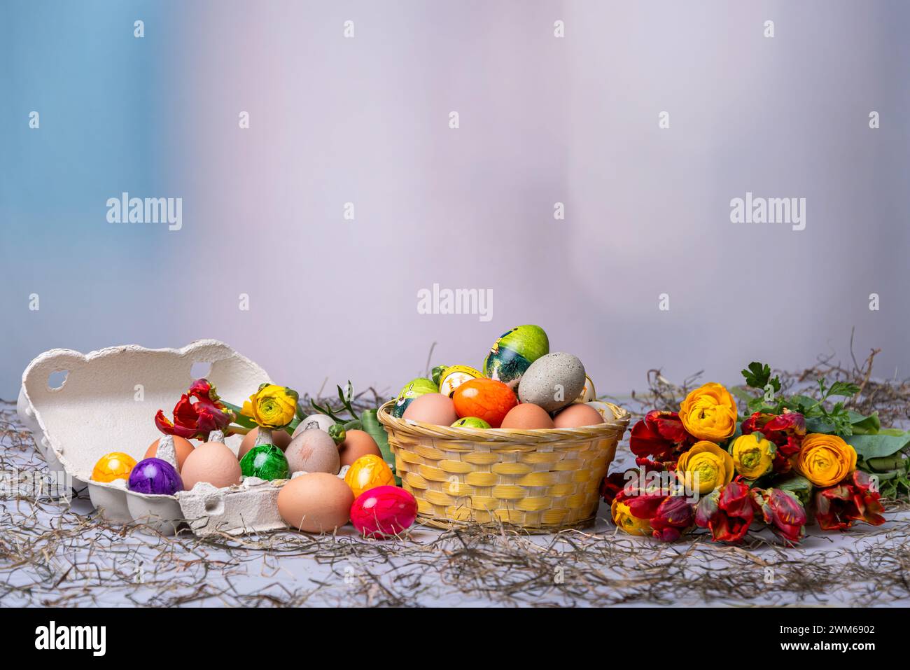 Bunte Ostereier auf einem Tisch mit Bumenstrauß als Postkartenmotiv zu Ostern Stock Photo