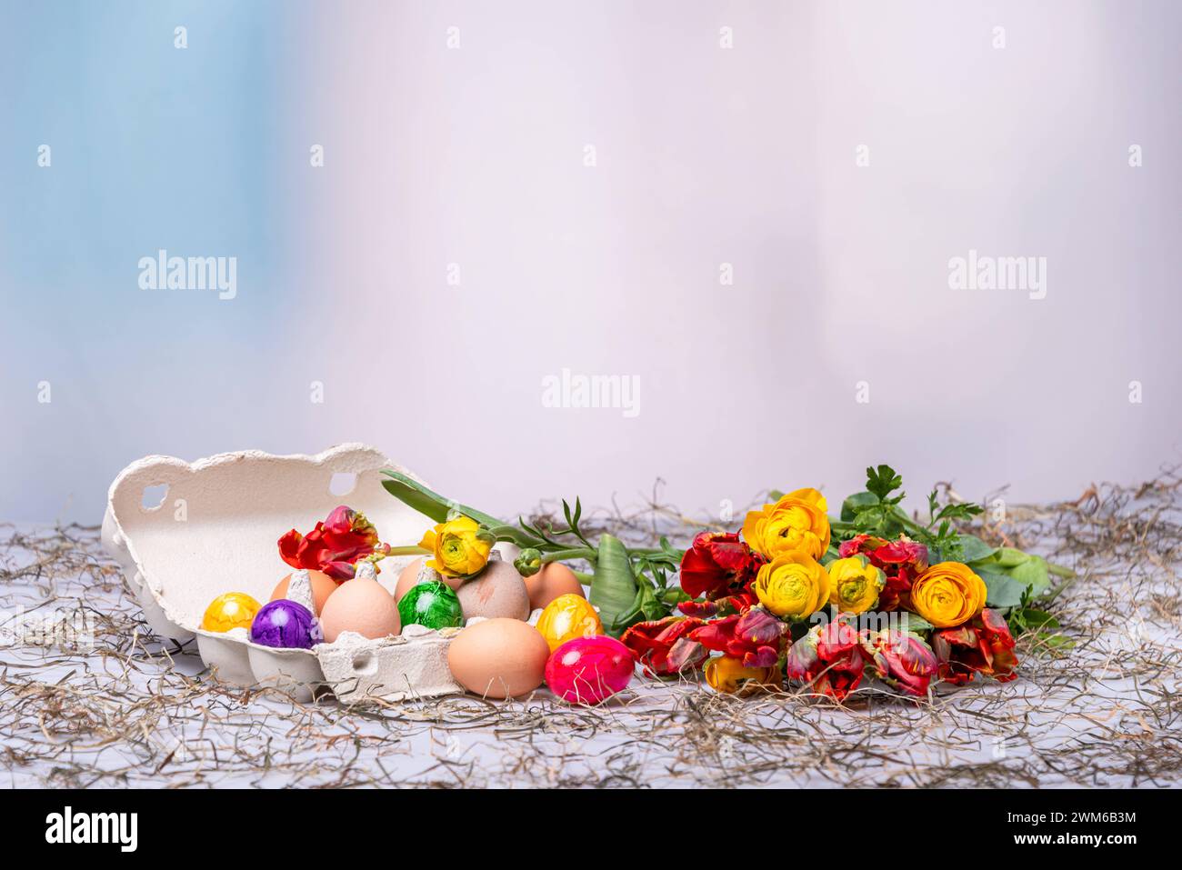 Bunte Ostereier auf einem Tisch mit Bumenstrauß als Postkartenmotiv zu Ostern *** Colorful Easter eggs on a table with a bouquet of flowers as a postcard motif for Easter Stock Photo