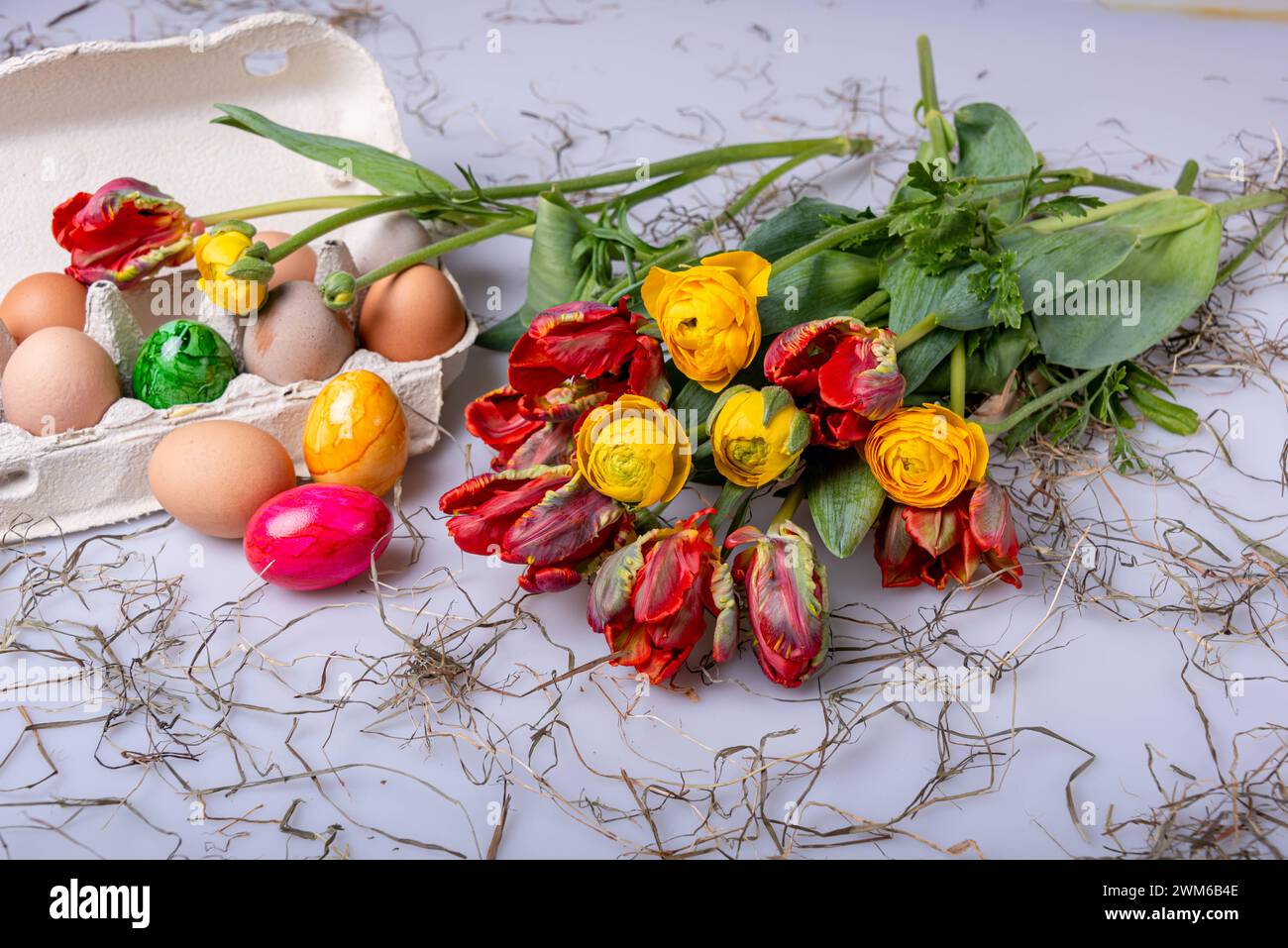 Bunte Ostereier auf einem Tisch mit Bumenstrauß als Postkartenmotiv zu Ostern *** Colorful Easter eggs on a table with a bouquet of flowers as a postcard motif for Easter Stock Photo