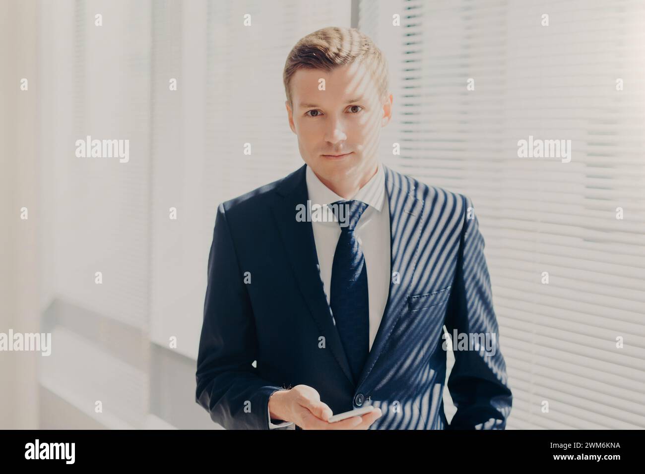 Polished businessman with a sharp look navigating the smartphone in a ...