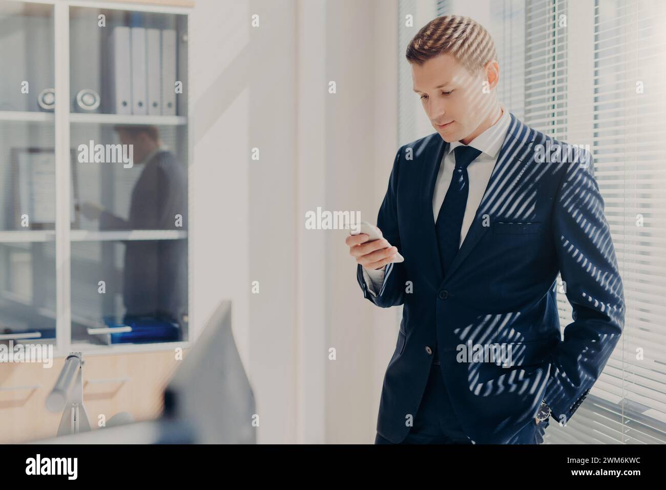 Composed businessman in pinstripe suit engaged with smartphone ...