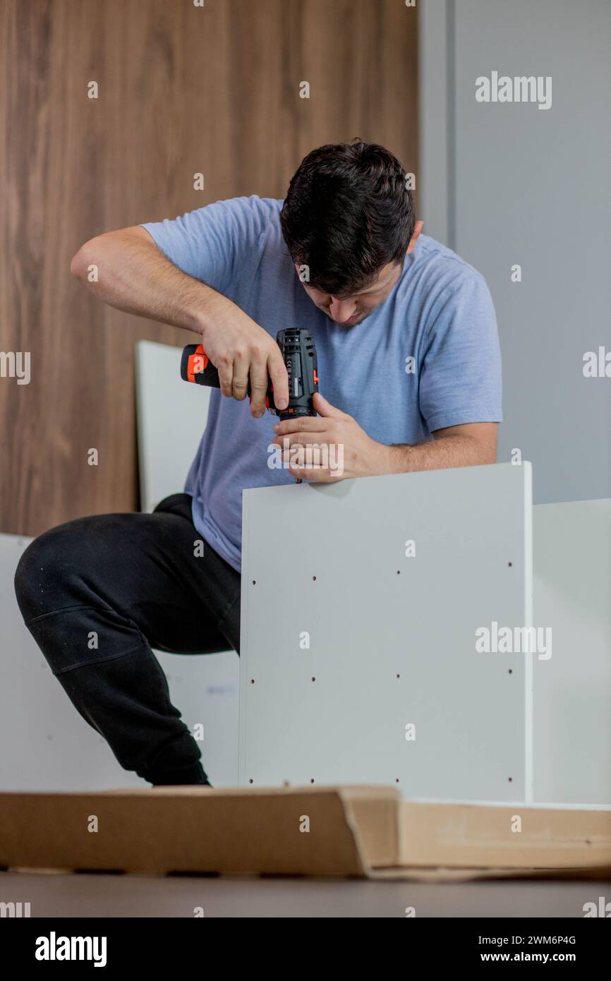 Man assembling furniture by using cordless screwdriver. Stock Photo