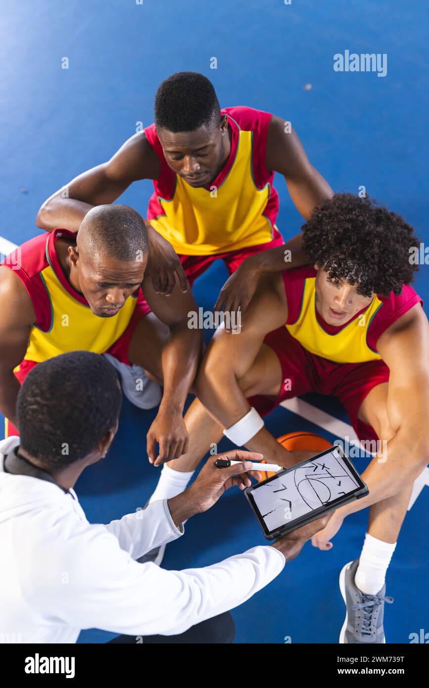 Diverse basketball team discusses strategy on court Stock Photo