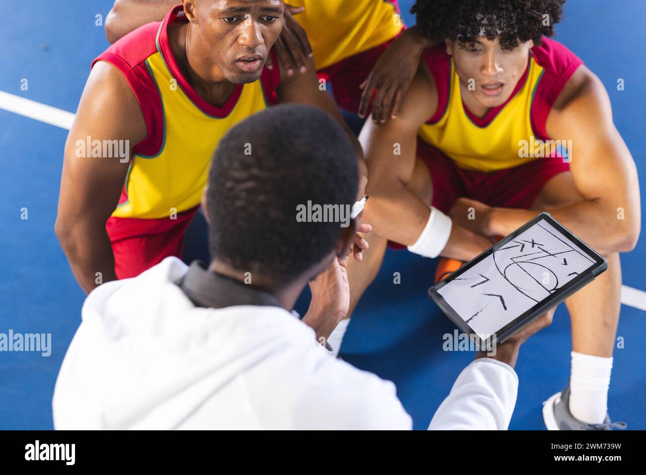 Diverse basketball team discusses strategy during a timeout Stock Photo