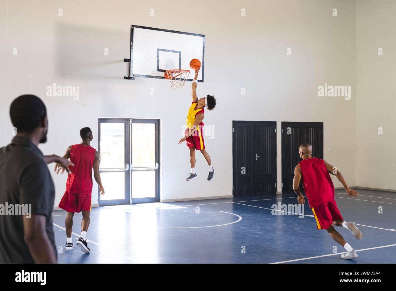 Young African American man jumps for a slam dunk in a basketball game at a gym Stock Photo