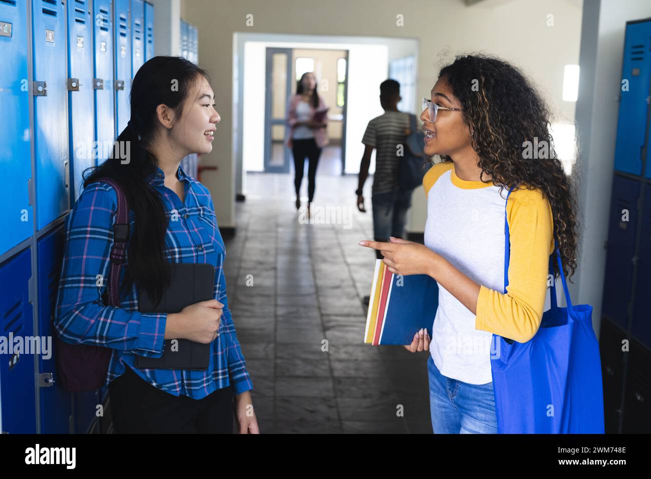 Teenage Asian girl chats with a biracial woman at high school Stock Photo