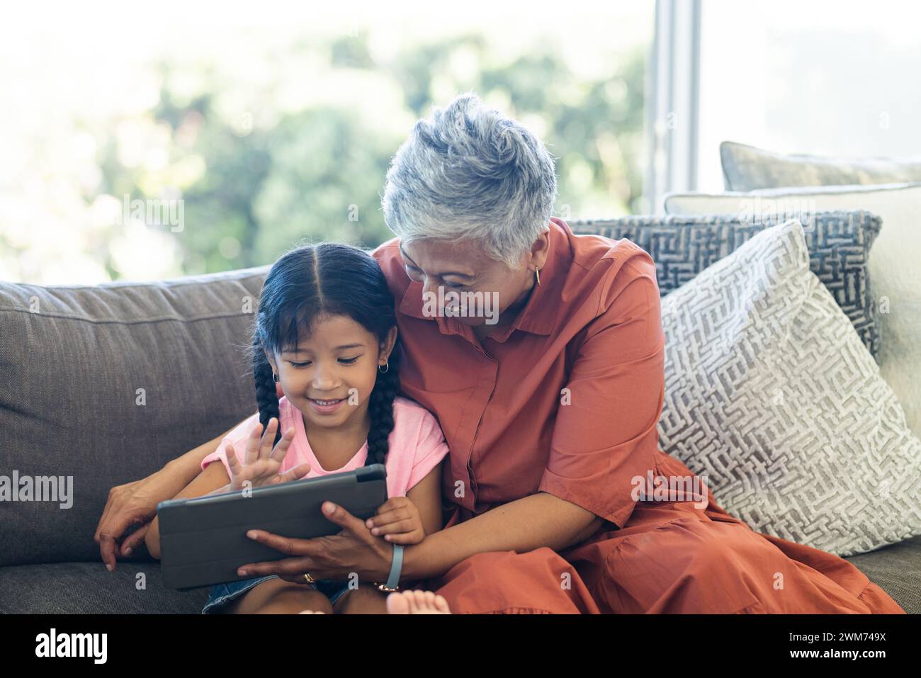 Biracial granddaughter and grandmother share a tablet at home Stock Photo