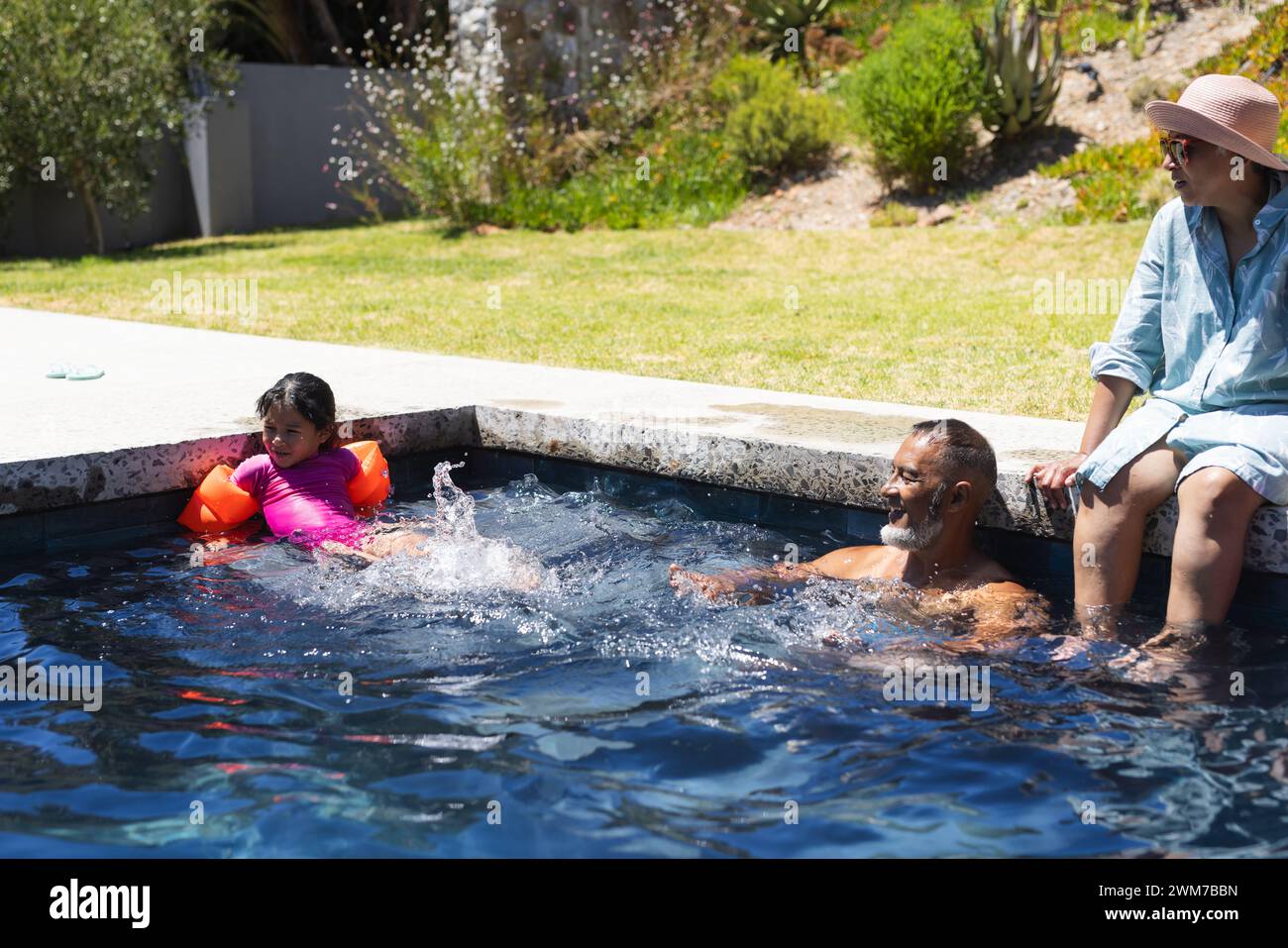 Biracial grandparents enjoy pool time on a sunny day Stock Photo