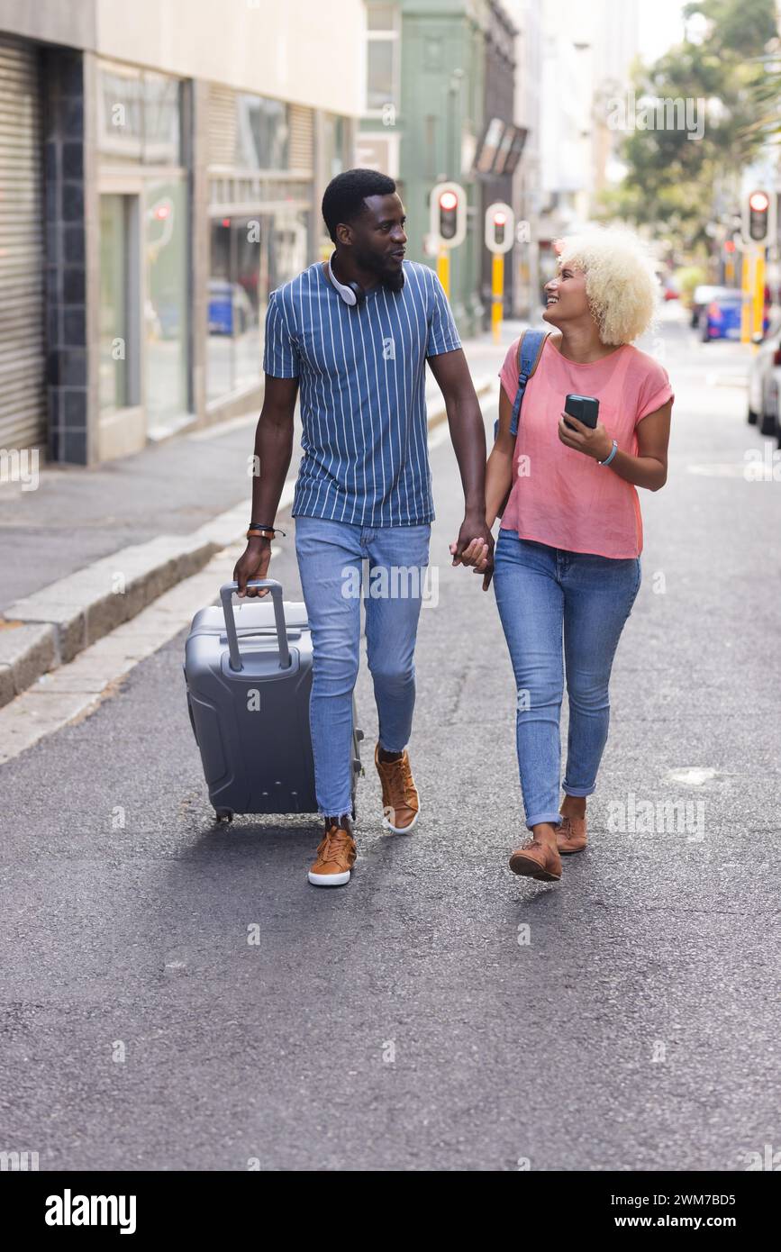 Diverse biracial couple walking on a city street on vacation Stock Photo