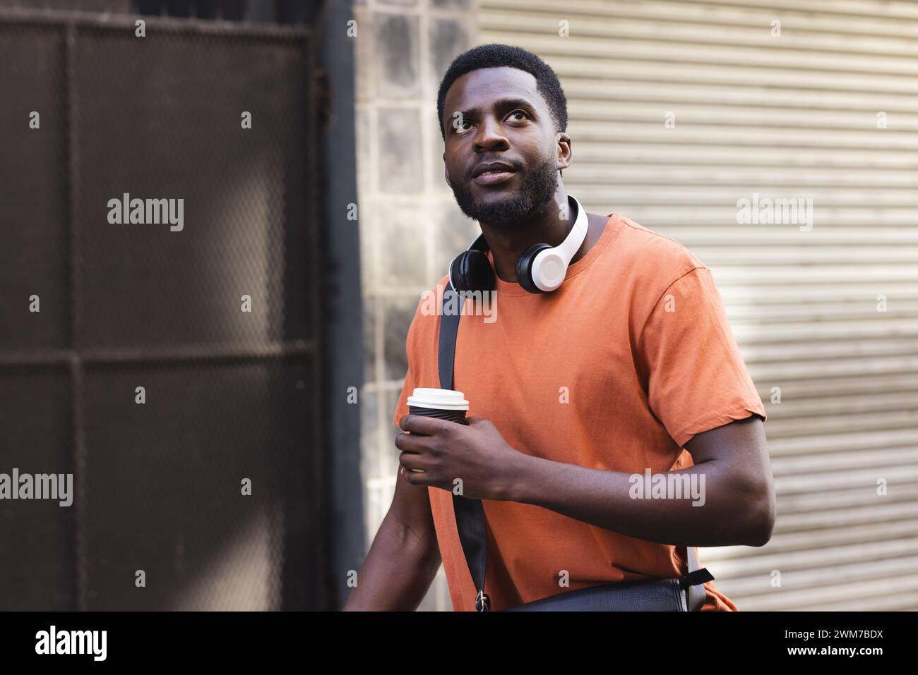 A young African American man holds a coffee cup outdoors in the city Stock Photo