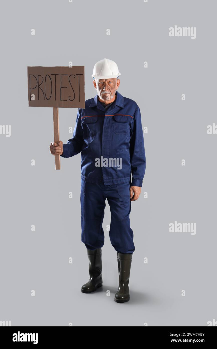 Protesting miner man with placard on grey background Stock Photo