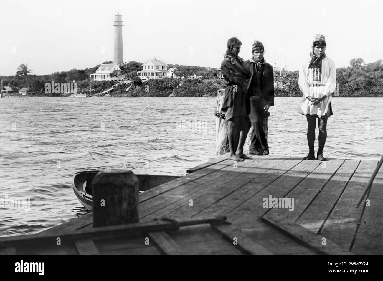 Seminole Indian men standing on a dock across the Jupiter Inlet from the Jupiter Lighthouse in Jupiter, Florida, 1880s. Stock Photo