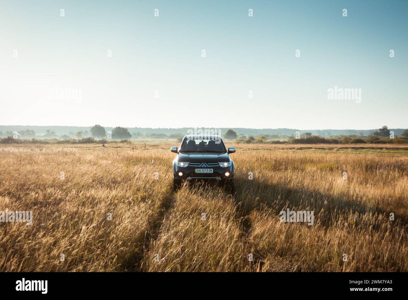 black Mitsubishi SUV pickup truck in a meadow. Morning light at 6am, symmetric view from the front Stock Photo