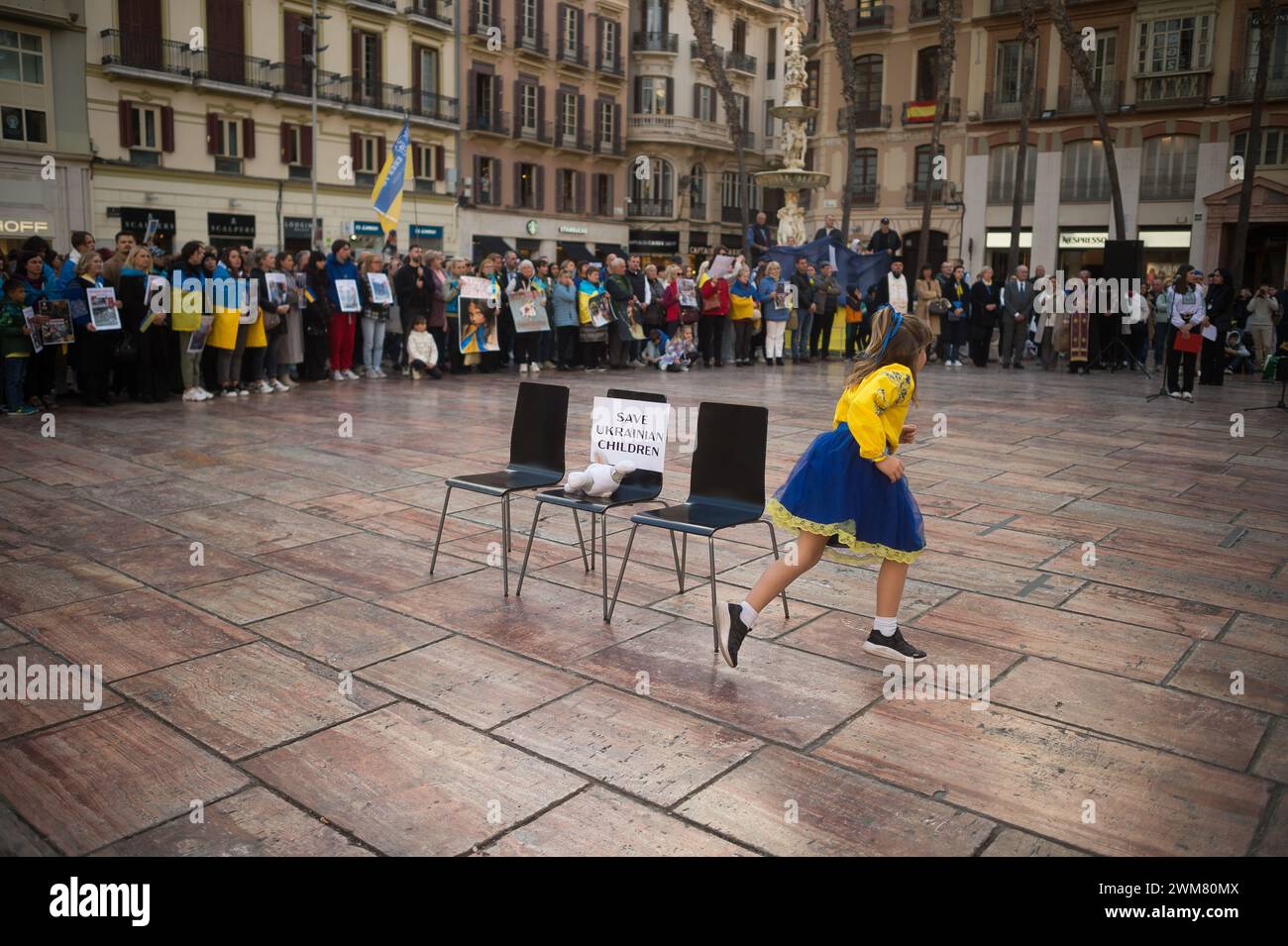 Malaga, Spain. 24th Feb, 2024. A girl is seen running during a performance denouncing war crimes against children as she takes part in an anti-war protest between Ukraine and Russia at Plaza de la Constitucion square. Marking the second anniversary of the Russian invasion of Ukraine, hundreds of people have gathered at Plaza de la Constitucion square in solidarity with Ukraine people, against the war and calling for peace. Credit: SOPA Images Limited/Alamy Live News Stock Photo