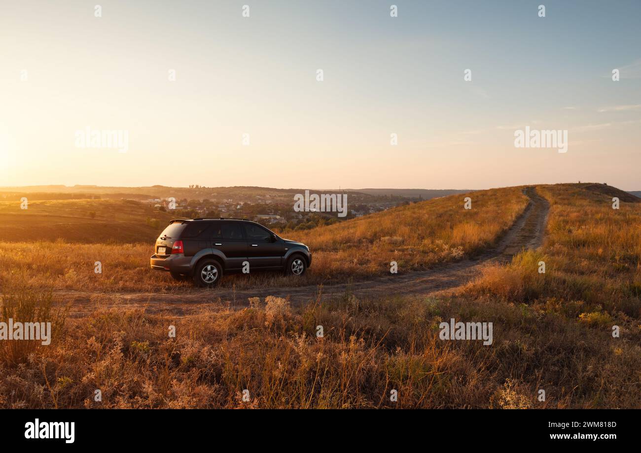 black KIA Sorento SUV on top of the hill. Warm sunset light Stock Photo
