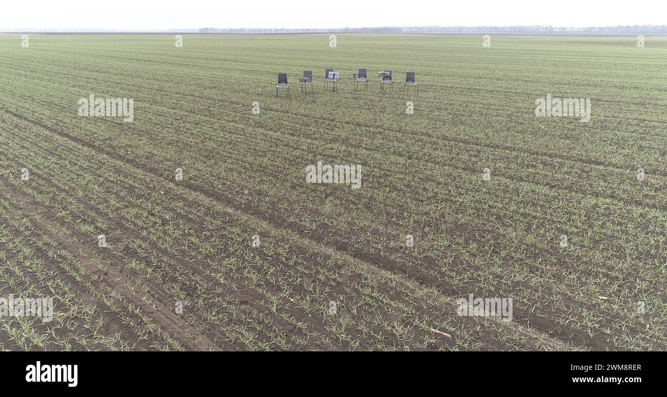 Six chairs in the middle of a empty winter crop field waiting for an orchestra musicians Stock Photo