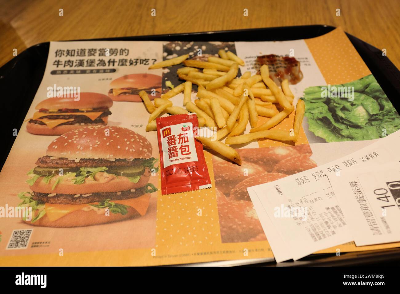 French fries, ketchup packet, and receipt on a tray with a liner in Chinese; McDonald's in Taipei, Taiwan; American fast food in Asia; globalization. Stock Photo