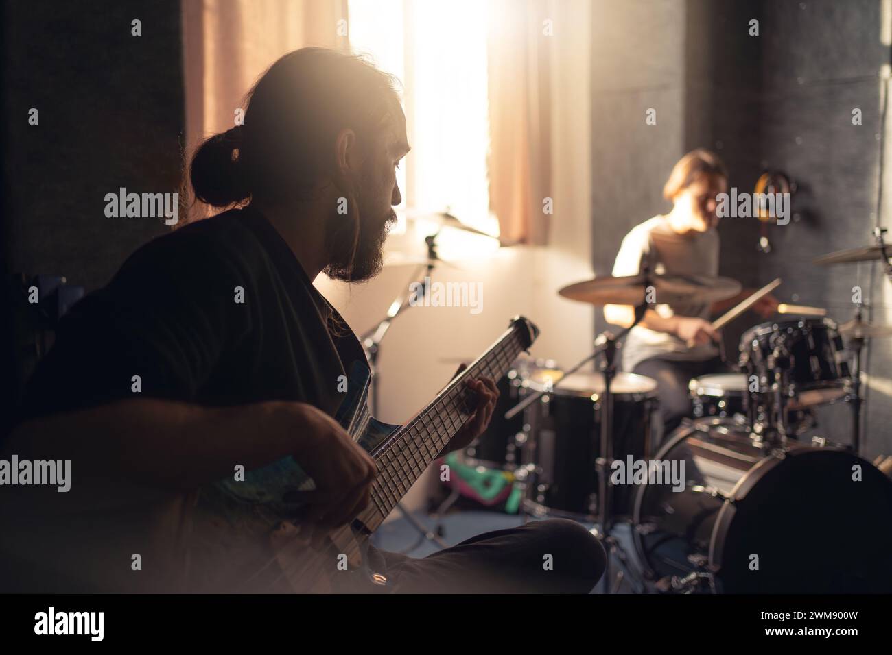 Band members practicing in a music studio with focus on guitarist. Stock Photo