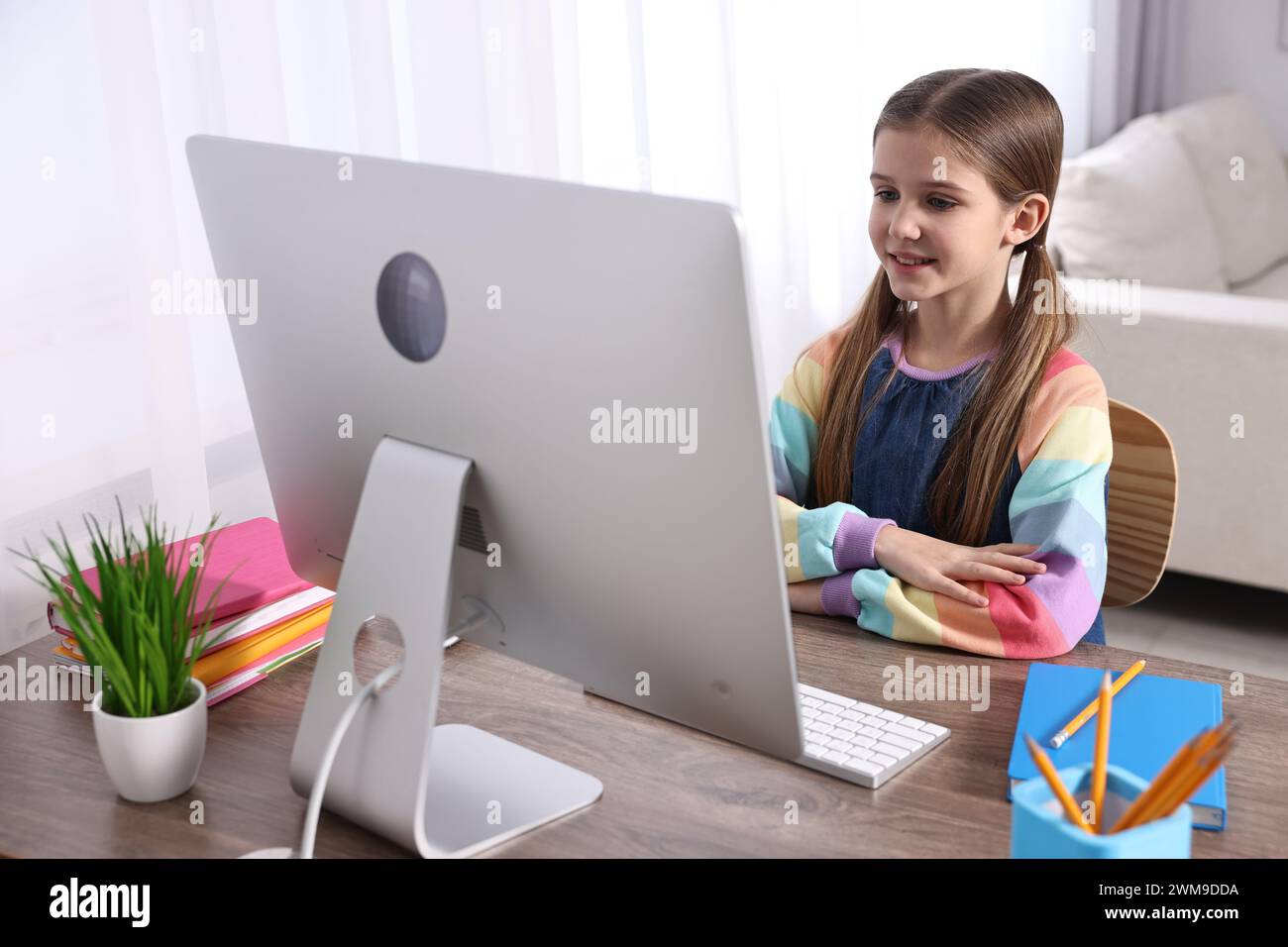 E-learning. Cute girl using computer during online lesson at table ...