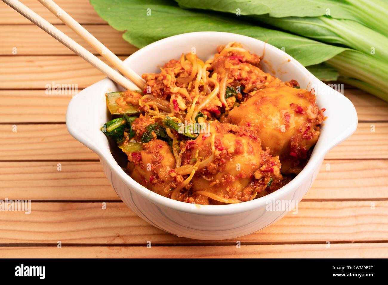 Fried dumplings in a white bowl. Made from wet dumplings that are sauteed with mustard greens, bean sprouts and spicy seasonings Stock Photo