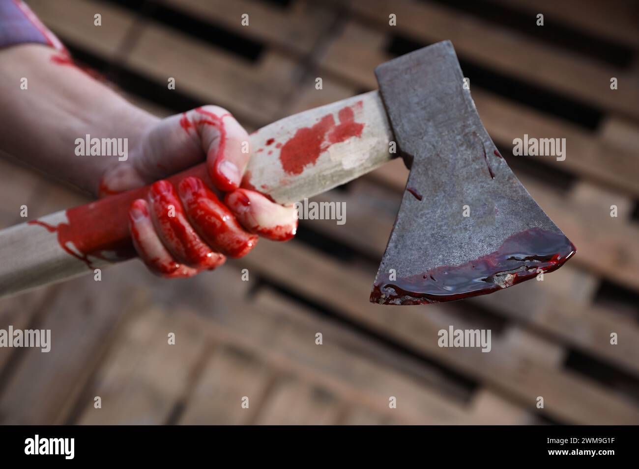 Man holding bloody axe outdoors, closeup view Stock Photo