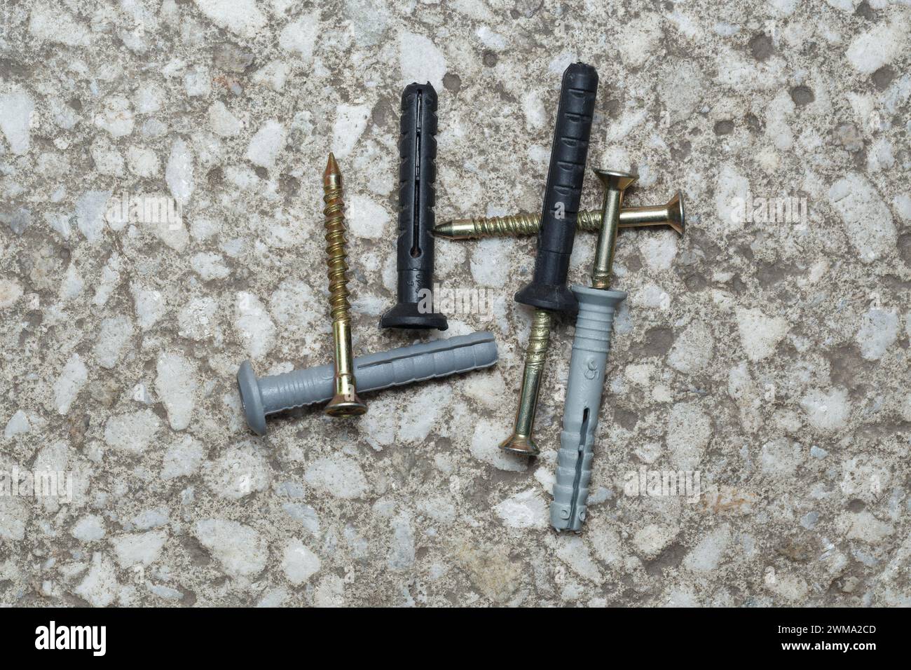 Gray and black dowel nails are scattered on the concrete base. Close-up. Stock Photo
