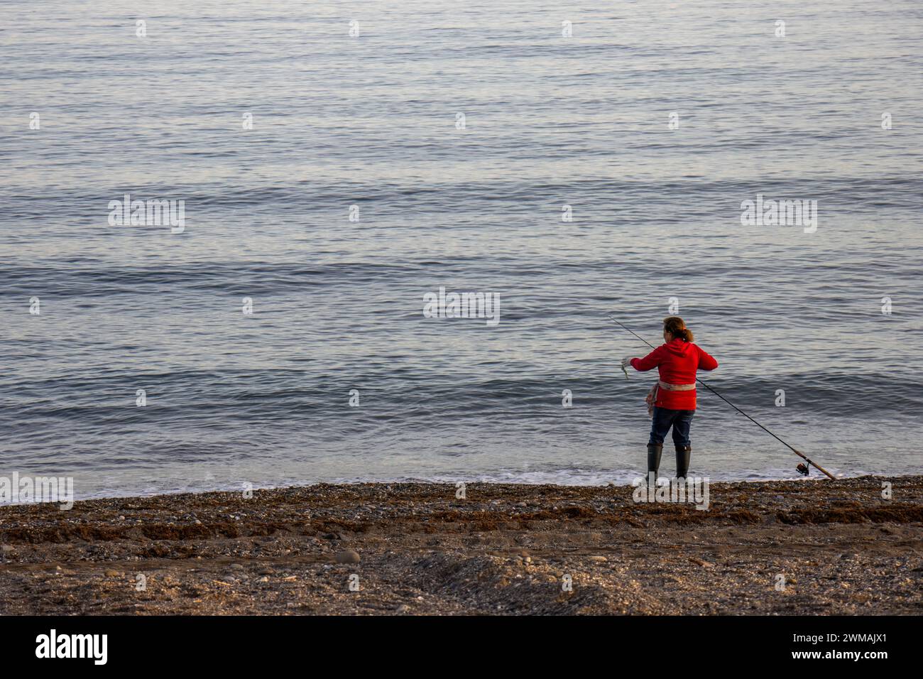 Mujer pescando con caña a la orilla del mar, San Pedro de Alcántara, Marbella, España Stock Photo