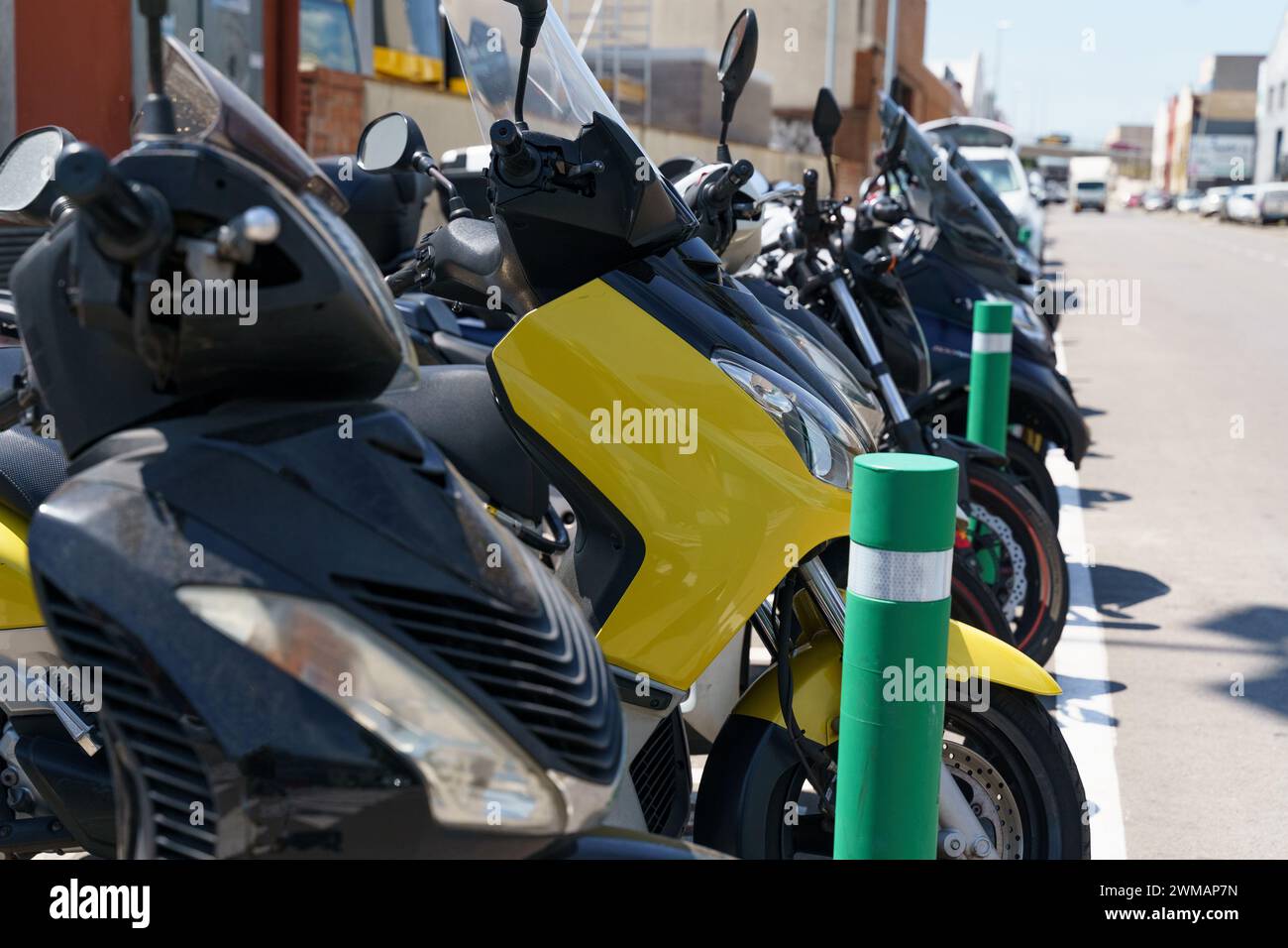 A row of motorcycles neatly lined up next to each other in a parking lot. Each bike is standing upright, showing off its unique design and details. Th Stock Photo
