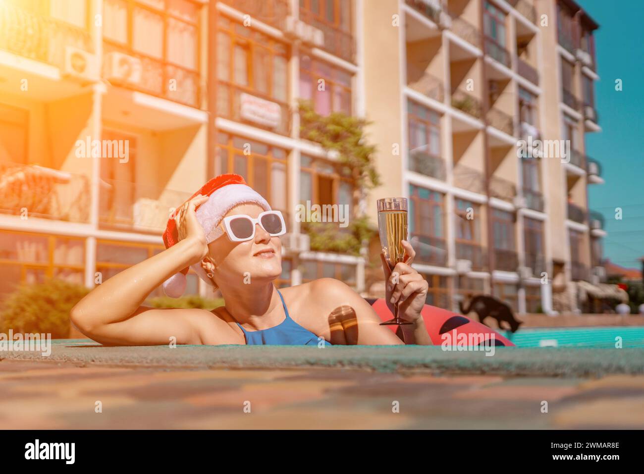 Woman pool Santa hat. A happy woman in a blue bikini, a red and white ...